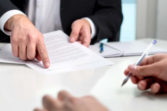 Attorney showing a client where to sign on their Will.