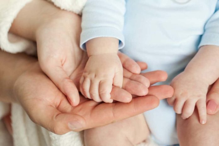 An adopted baby holding her mother's hand