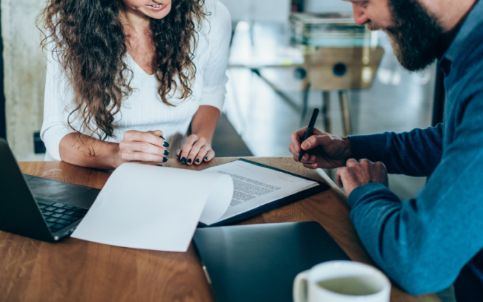 man and woman sitting at table signing forms