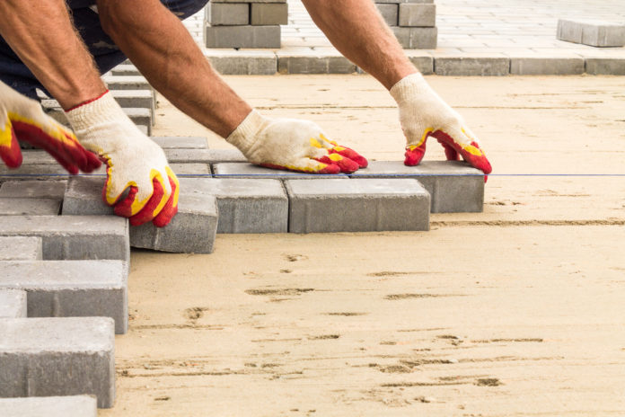 workers lay paving tiles