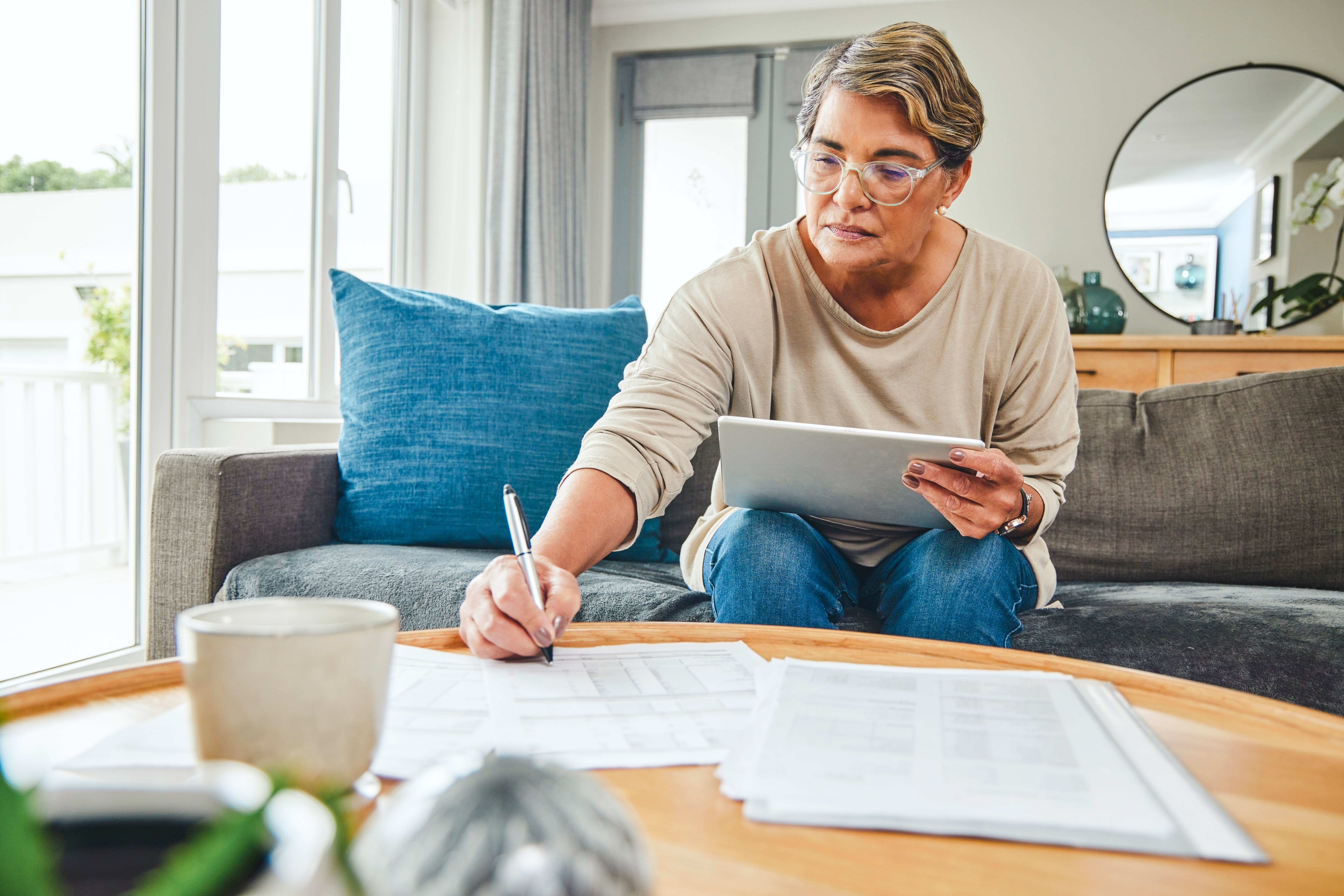 woman using a digital tablet while going through paperwork at home