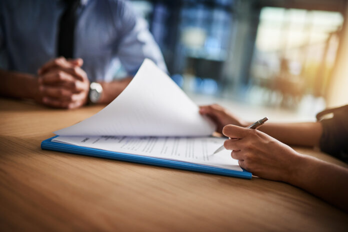Person holding a pen and reading a legal document
