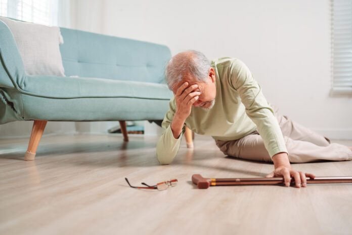Senior man falling on the ground with walker in living room at home.