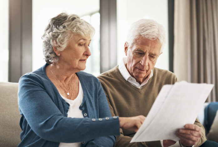 Senior couple, documents from bank and reading in living room, sofa or home mortgage agreement, papers and loan contract. Elderly people, bills and financial planning, investment or management of tax