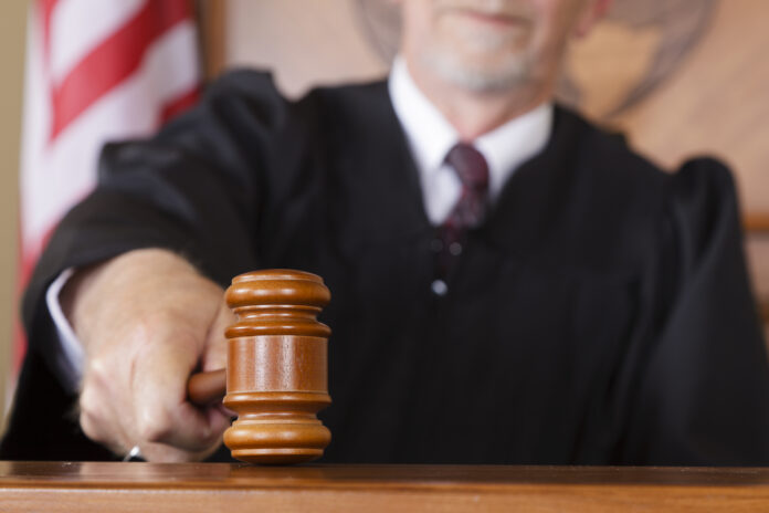 A close-up of a judge's gavel in his hand in the courtroom.