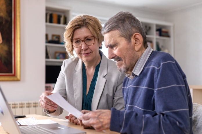 Mature woman helping senior man, 91 years old, with paperwork. He signing documents
