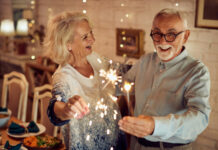 Happy mature couple using sparklers and having fun together on Christmas day at home.